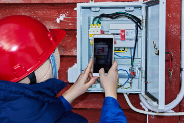 An employee of energy sales company takes readings of outdoor electricity meter in private...