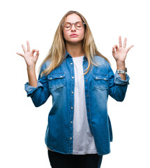 Young beautiful blonde woman wearing glasses over isolated background relax and smiling with eyes closed doing meditation gesture with fingers. Yoga concept.