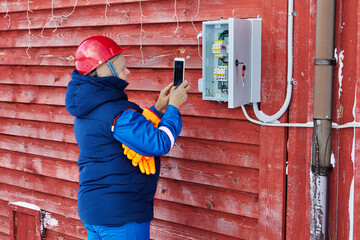 An energy supply company specialist inspects outdoor electrical equipment of private household in...