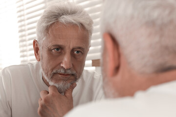 Fototapeta premium Senior man looking in mirror at home