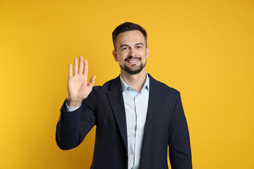 Man making promise with raised hand on orange background. Oath gesture