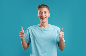 Happy man showing thumbs up on light blue background. Like gesture