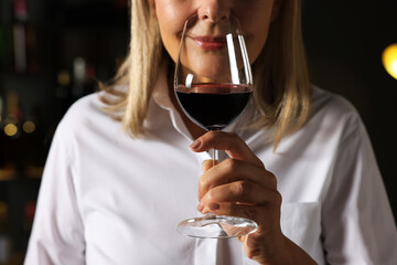 Professional sommelier tasting red wine indoors, closeup