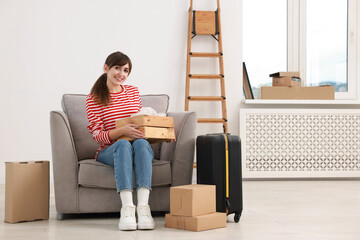 Happy woman with moving boxes and suitcase in new apartment. Housewarming party
