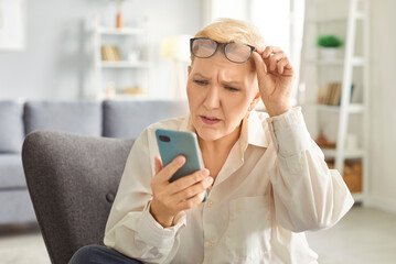 Shocked in worry, concerned mature woman in glasses holding smartphone, staring at phone screen in surprise, getting stress, bad news, message, financial problems, money stealing, bankruptcy risk
