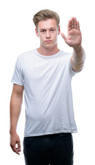 Naklejka premium Young handsome blond man with open hand doing stop sign with serious and confident expression, defense gesture