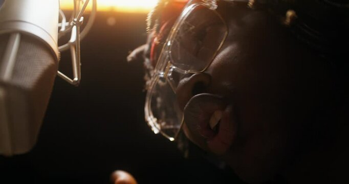 A rapper sings into a microphone in a recording studio. Close-up of his face