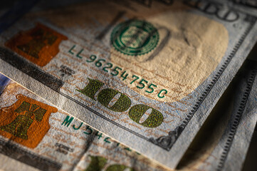 Fototapeta premium Close-up view of a 100 dollar bill with details, security features and vibrant colors. Finance, banking and wealth representation theme, low key, selective focus