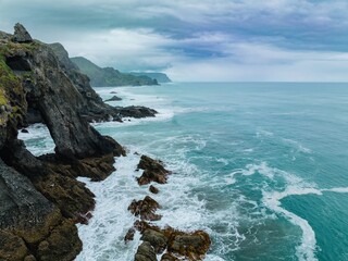 Ocean waves crashing against dramatic coastal rock formations. Powerful waves against rugged...