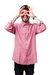 Fototapeta premium Young handsome man wearing pink shirt over isolated background doing ok gesture like binoculars sticking tongue out, eyes looking through fingers. Crazy expression.