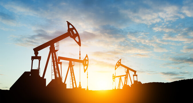 Oil drilling derricks at desert oilfield. The change in oil prices caused by the war. Oil price cap concept.