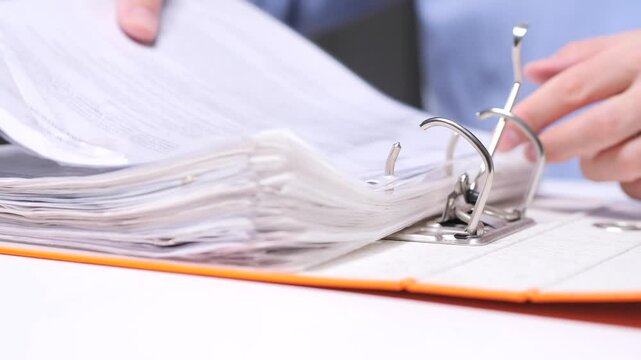 Office worker inserting documents into folder binder