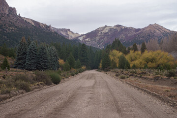 Fototapeta premium RP65, Neuquen Province, Argentina - May 10th, 2023 - View of a dirt road with mountains in the background on a cloudy day near Bariloche.