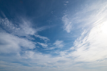 Obraz premium Weiße Schleierwolken vor einem milchig-blauen Himmel und gegen die Sonne