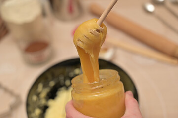 Christmas homemade baking, ingredients for baking gingerbread, woman with honey dipper added honey...