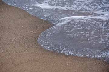 A wave crashing onto a sandy beach