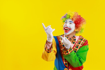 Portrait of happy clown on yellow background, space for text