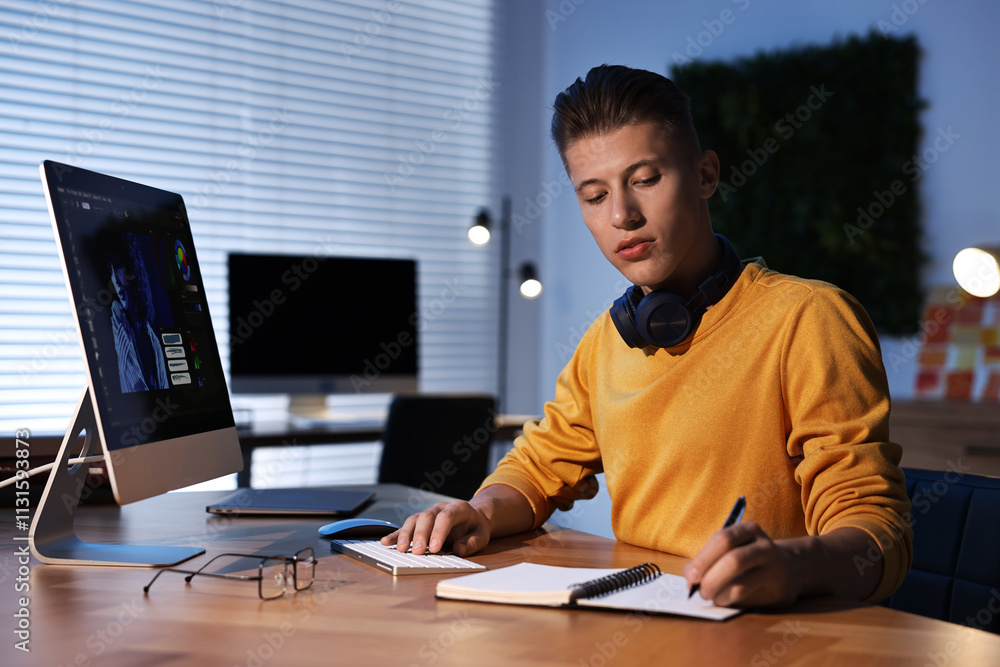 Aufkleber designer taking notes while working on computer indoors at night