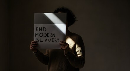 Shadowed figure holding sign that reads "End Modern Slavery"