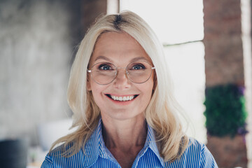 Confident senior businesswoman smiling in modern office with natural daylight
