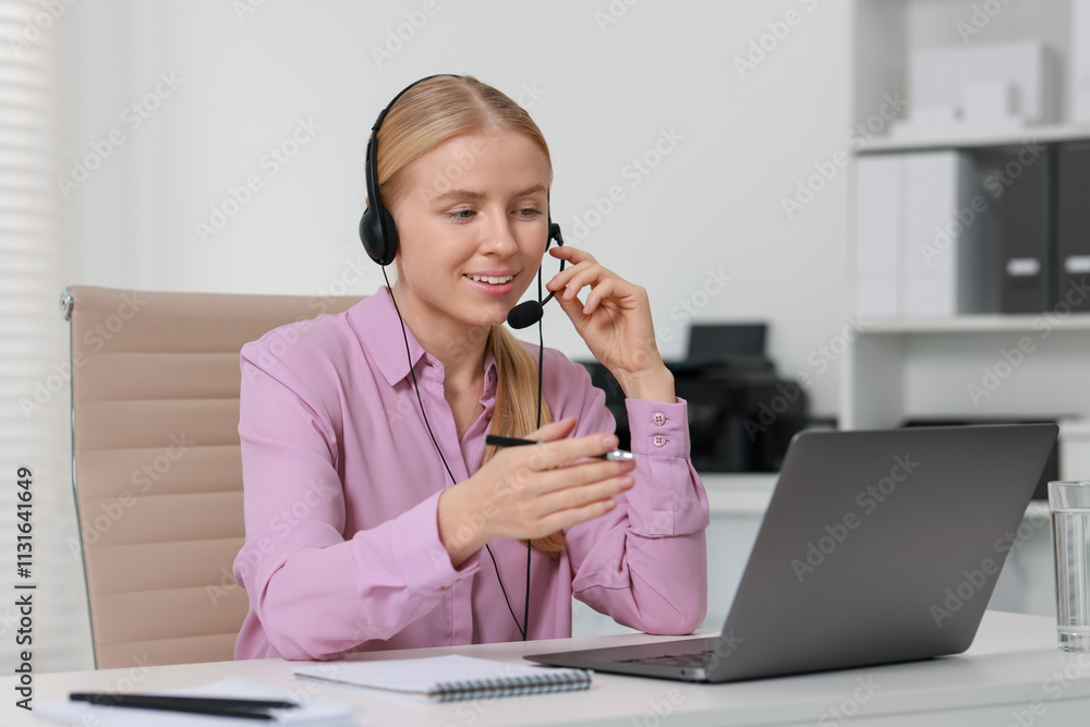 Poster interpreter in headset having video chat via laptop at table indoors