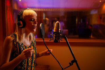 Professional singer recording song in music recording studio.