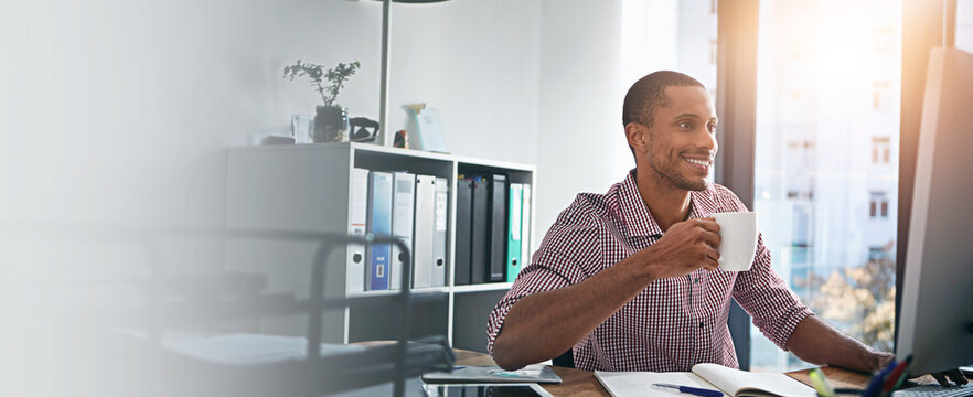Computer, coffee and smile with designer man at desk in office for development, planning or research. Banner, mockup and space with happy employee in workplace for online review of information