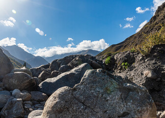 large boulder stones against the background of mountains with blue sky and clouds. natural light