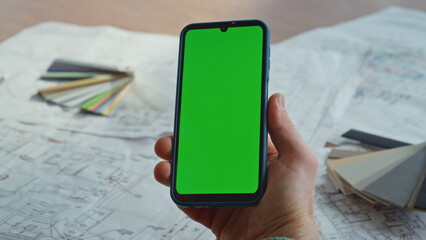 Manager hand holding green screen smartphone in architectural agency closeup.