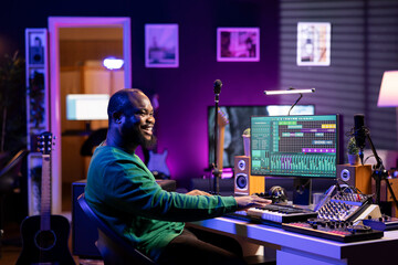 Male artist producing music on electronic piano keyboard in home studio. Sound engineer playing...