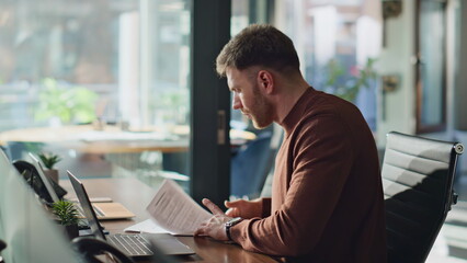 Smart businessman reviewing papers in office closeup. Manager working documents 
