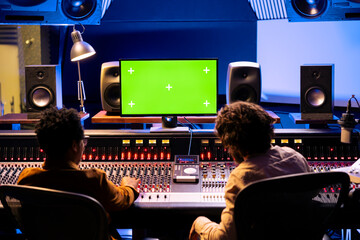 Team of audio experts mixing and mastering music next to mockup in control room, editing new tracks...