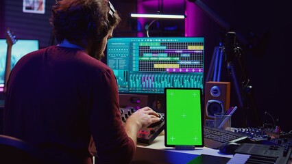 Music producer songwriter mixing tunes on stereo console, recording sounds next to tablet with...