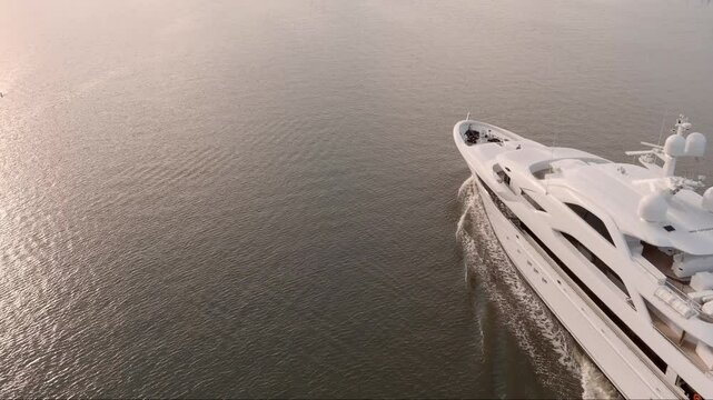 Aerial close up shot of mega yacht moving across the ocean at sunrise. Yacht has no name or logos.