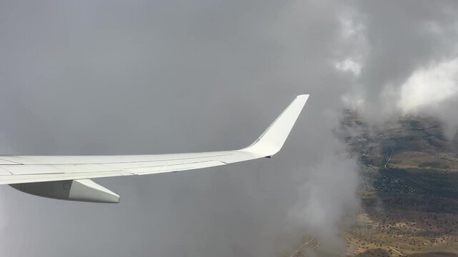 Airplane wing soaring above fluffy white clouds with a clear blue sky and a breathtaking aerial view of the horizon