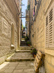 Obraz premium Korcula, Croatia - June 30, 2024: Look from the west into the street, an alley with steps named Vinka Foretica. Colored laundry on balcony, flowers pots along the way and transport pallet