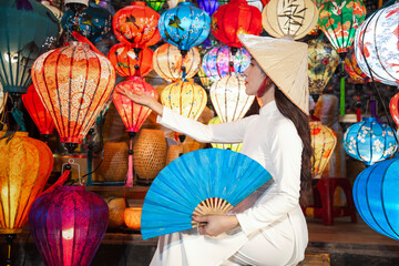 Woman wearing traditional Vietnamese culture with white, colorful lanterns at Hoi An ancient city...