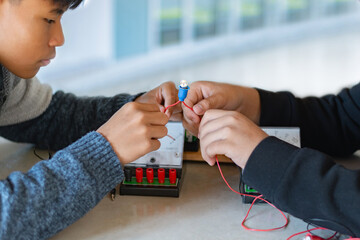 Children are studying electrical circuit systems by experimenting with electrical connections using...
