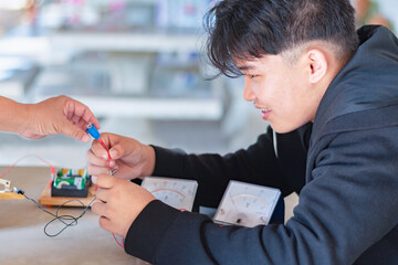 Children are studying electrical circuit systems by experimenting with electrical connections using...