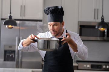 modern chef in professional uniform. close-up on the hand of male chef who is stirring soup in pot...
