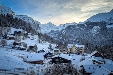Scenic view of Wengen and Lauterbrunnen Valley, Switzerland with snowcovered mountains in winter against blue sky at sunset