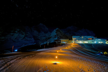 Torches showing the way to Berghaus Maennlichen at night in winter, Grindelwald, Switzerland with...