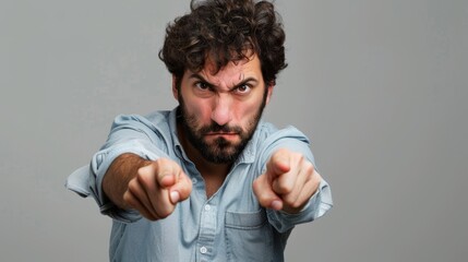 A man in a casual shirt points forward with an intense and serious expression, conveying focus and confrontation..