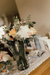 A delicate wedding table decoration featuring fresh white and pink roses, greenery, and a wooden handle accent. placed on a lace runner, the scene radiates charm, romance, and elegant rustic beauty.