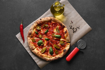 Tasty pizza, oil, spices and cutter on dark background