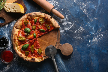 Composition with tasty pizza, ingredients and cutter on blue background