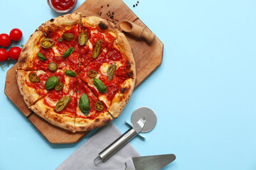 Composition with tasty pizza, ingredients and cutter on blue background