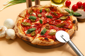 Tasty pizza, ingredients and cutter on beige background