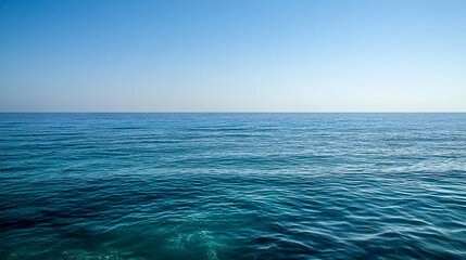 Obraz premium Serene view of a calm ocean under a clear blue sky, evoking tranquility and peace.