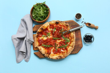Composition with tasty pizza, ingredients and cutter on blue background
